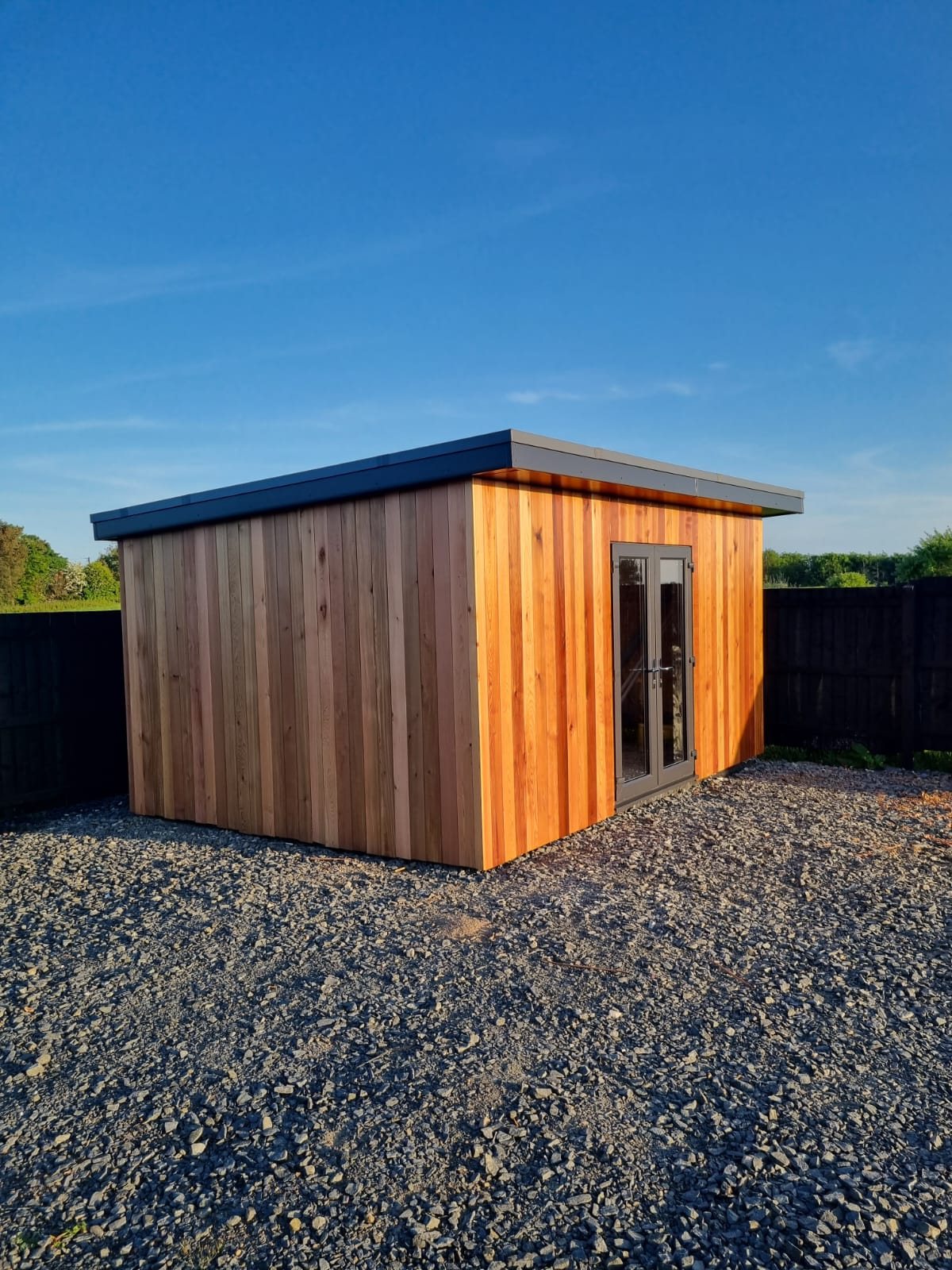 Garden room with vertical timber cladding and glazed doors, seen from the front